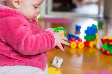 Ahşap zemin üzerinde renkli tuğla ile oynayan bebek.