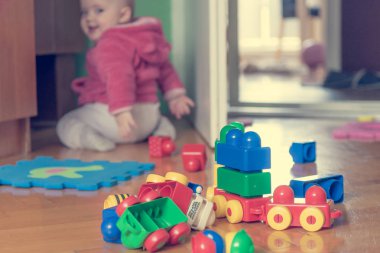 Ahşap zemin üzerinde renkli tuğla ile oynayan bebek.