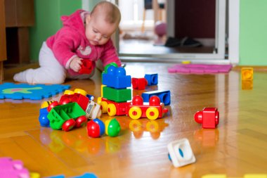 Ahşap zemin üzerinde renkli tuğla ile oynayan bebek.