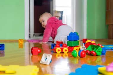 Ahşap zemin üzerinde renkli tuğla ile oynayan bebek.