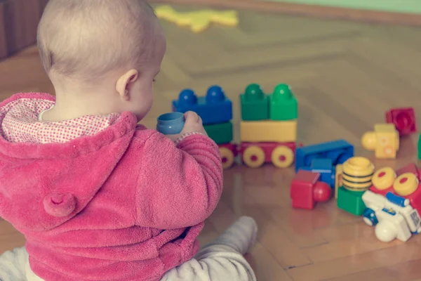 Bebé jugando con ladrillos de colores en el suelo de madera . —  Fotos de Stock