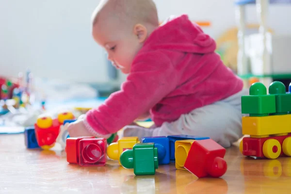 Bebé jugando con ladrillos de colores en el suelo de madera . —  Fotos de Stock
