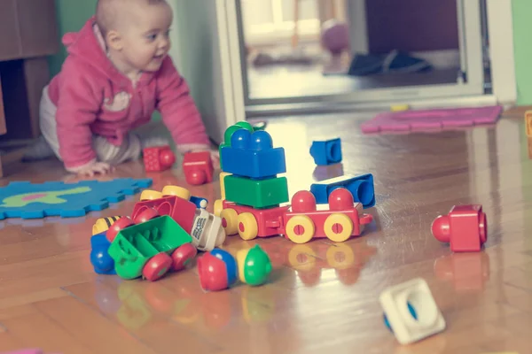 Baby leker med färgglada tegelstenar på trägolv. — Stockfoto