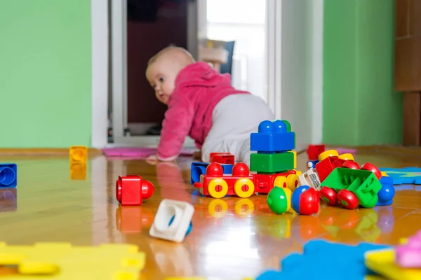 Дитина грає з барвистими цеглинами на дерев'яній підлозі . — стокове фото