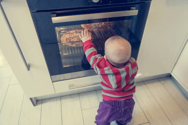 Child pushing at active oven.