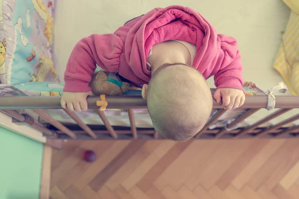 Дитина стоїть в ліжку і спирається на бік ліжка . — стокове фото