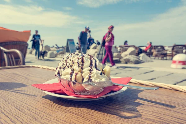 在海边的人行道上吃美味的香蕉分冰淇淋. — 图库照片