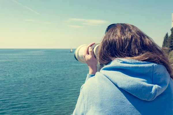 Woman looking through coin operated binoculars at seaside. — Stock Photo, Image