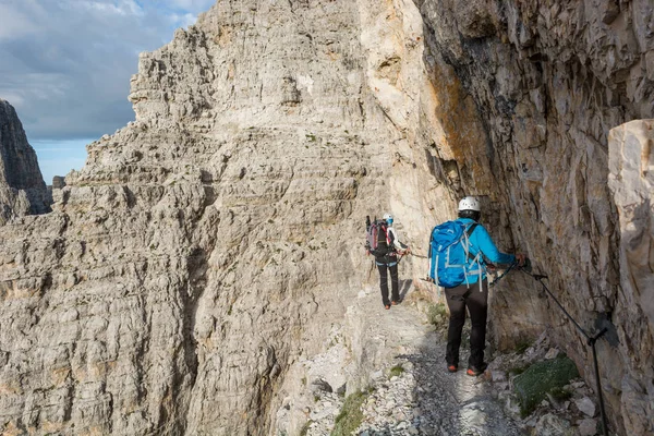 狭い棚の上を歩く登山者のペア. — ストック写真