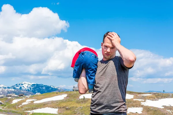 Joven padre sosteniendo a su hijo por un lado sin saber qué hacer . — Foto de Stock