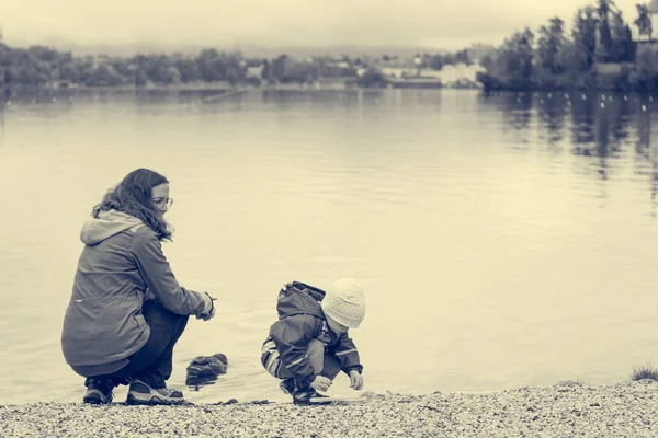 Mãe e filha brincando na margem do lago com igreja romântica no bacground . — Fotografia de Stock