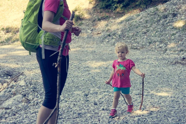 Caminhadas de mãe e filha com postes de caminhada em um caminho de montanha . — Fotografia de Stock