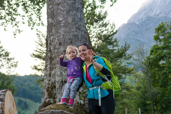 Mor försörjer sin dotter stående på trädstam och utforskar skogsutsikten i bergen. — Stockfoto