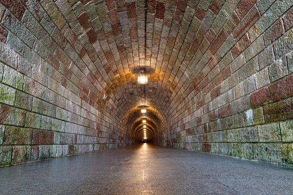 Tunel biegnący przez góry oświetlony światłami elektrycznymi. Zdjęcie Stockowe