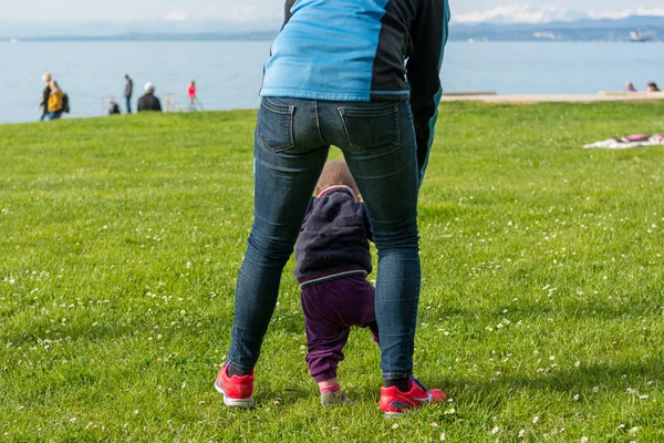 Carina bambina imparare a camminare con sua madre in un parco . — Foto Stock
