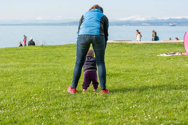 Menina bonito aprender a andar com sua mãe em um parque . — Fotografia de Stock