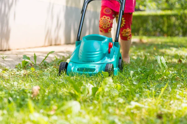 Deatyl plastikowej kosiarki lwn z dzieckiem pchając go. Zdjęcia Stockowe bez tantiem