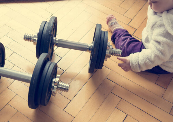 Drop down view of a child playing with a set of barbells.