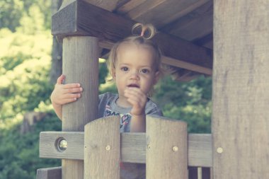 Tahta evde oynayan sevimli sarışın kız pencereden bakıyor..