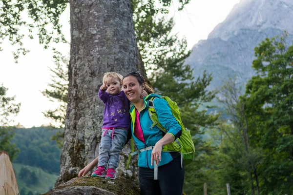 Matka podporující svou dceru stojící na kmeni stromu zkoumání lesního výhledu v horách. — Stock fotografie