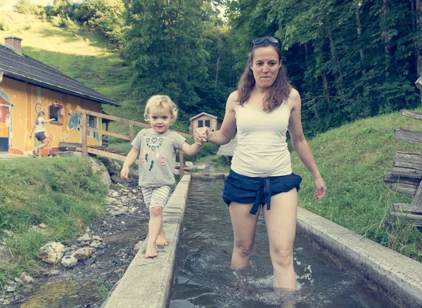 Mãe e filha se divertindo andando através do tanque de água no parque infantil ao ar livre . — Fotografia de Stock