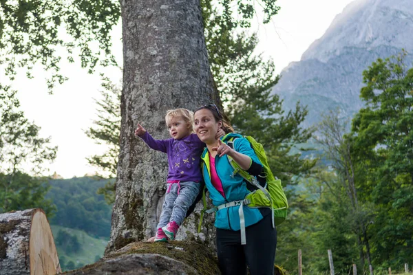Mor försörjer sin dotter stående på trädstam och utforskar skogsutsikten i bergen. — Stockfoto
