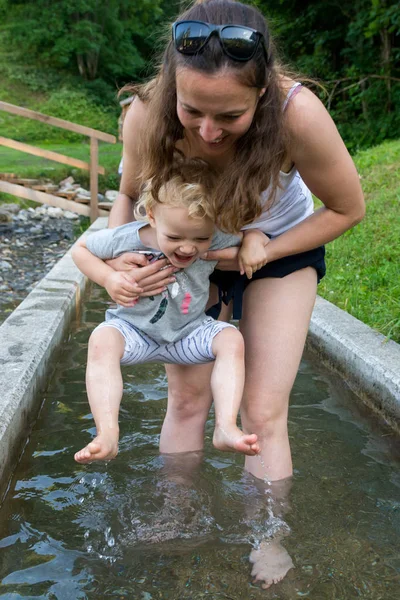 Madre e hija se divierten caminando a través del tanque de agua en el patio al aire libre . — Foto de Stock