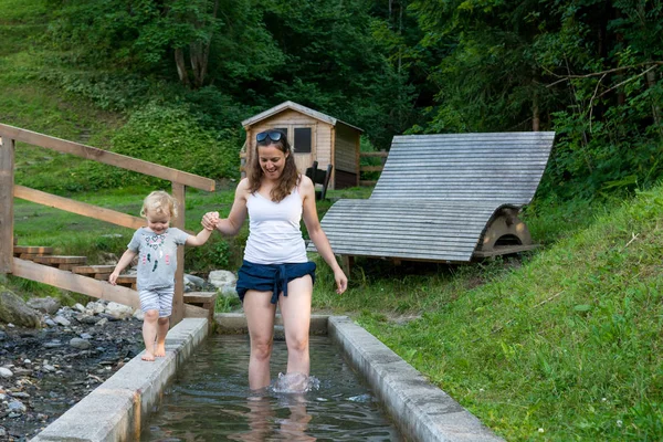 Mutter und Tochter haben Spaß beim Spaziergang durch Wassertank auf Spielplatz im Freien. — Stockfoto