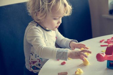 Bir sürü renkli çörekle oynayan tatlı bir kız..