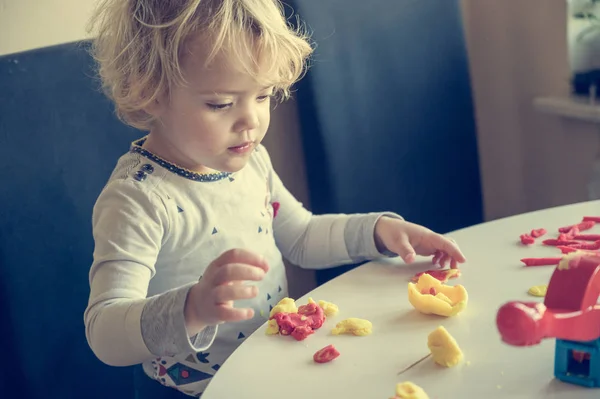 Aranyos lány játszik sok színes tészta. — Stock Fotó