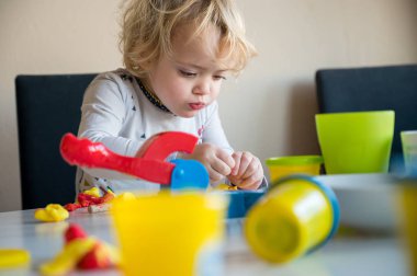 Bir sürü renkli çörekle oynayan tatlı bir kız..