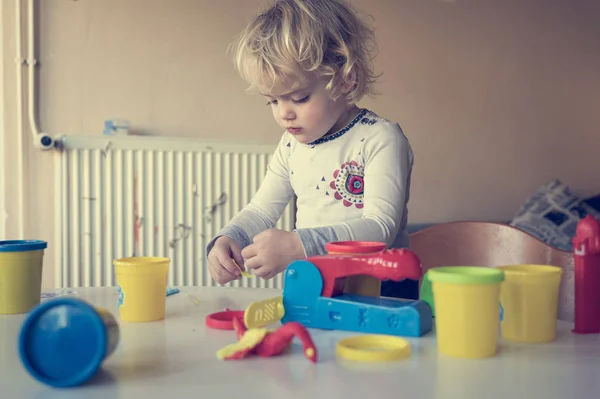 Aranyos lány játszik sok színes tészta. — Stock Fotó