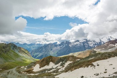 Gökyüzünü kaplayan bulutlarla muhteşem bir dağ manzarası.