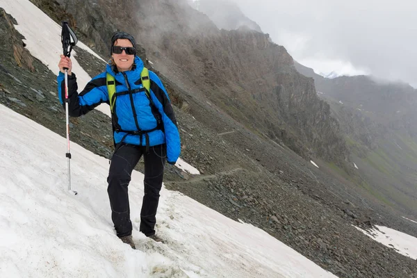 Femme alpiniste debout sur une pente enneigée dans les montagnes . — Photo