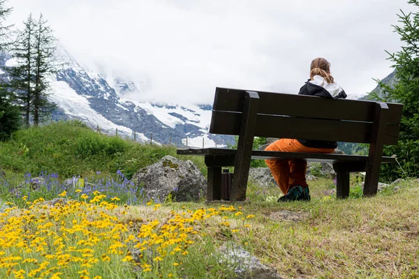 Ahşap bir bankta oturan kişi dağ manzarasının tadını çıkarıyor.. — Stok fotoğraf