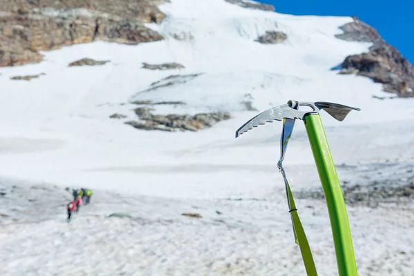 Pic à glace positionné dans la neige avec des alpinistes marchant en arrière-plan . — Photo