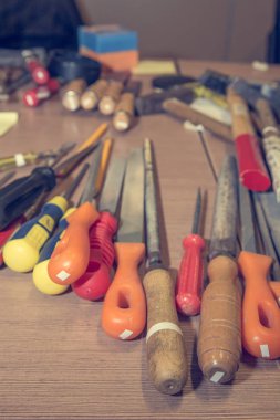 Different hand tools stacked on a wooden table.