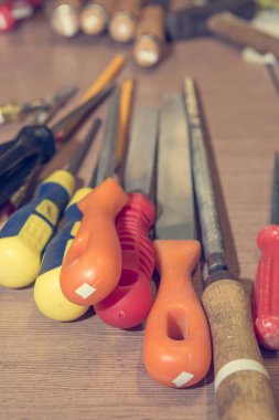 Different hand tools stacked on a wooden table.