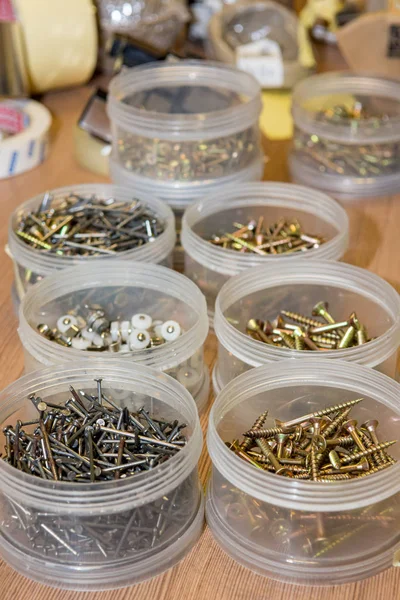 Screws and nails divided in plastic cups based on size. — Stock Photo, Image