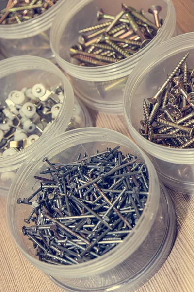 Screws and nails divided in plastic cups based on size. — Stock Photo, Image