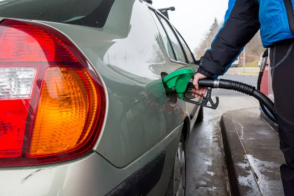 Detail view of hand holding fuel nozzle at petrol station. — Stock Photo, Image