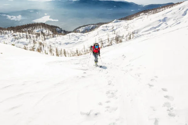 Female ski tourer ascending a snowy slope. — Stock Photo, Image