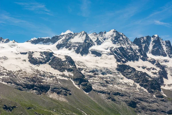 Spectacular mountain panorama with peaks and slopes covered with glaciers above lush green valley. — Stock Photo, Image