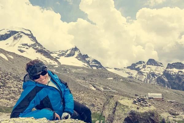Female mountaineer resting on a rock surrounded by spectacular mountain views. — Stok fotoğraf