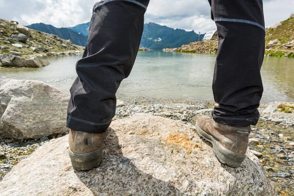 Low angle view of feet standing on a rock above mountain lake. — Stock Photo, Image