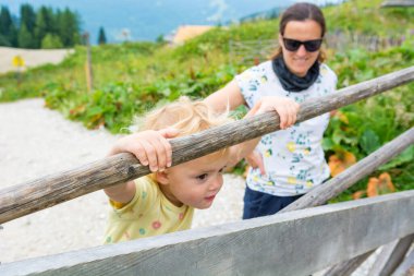 Dağdaki çitlerden tırmanan tatlı sarışın kız..