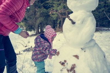 Anne ve kızı bir kardan adam yapıyor..