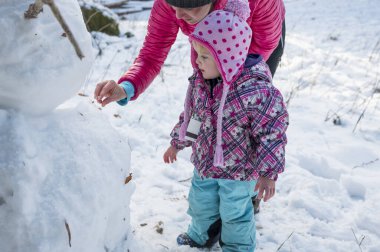Anne ve kızı bir kardan adam yapıyor..
