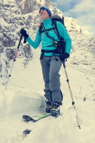 Female ski tourer ascending snow covered mountain slope. — Stock Photo, Image