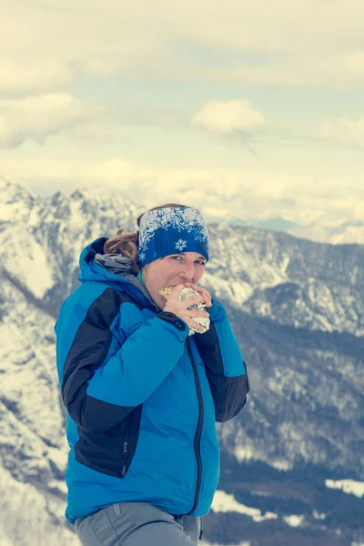 Alpinista donna che mangia un panino sulle montagne innevate . — Foto Stock